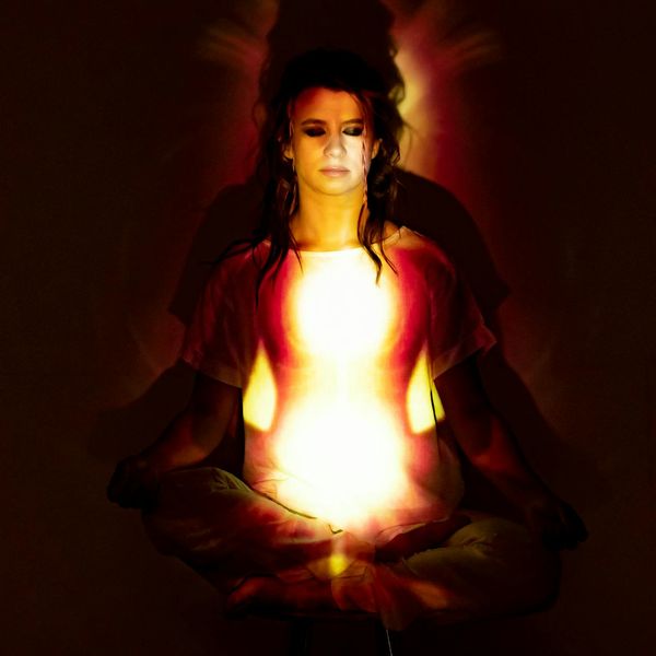 Silhouette of a woman meditating with a glowing energy aura.